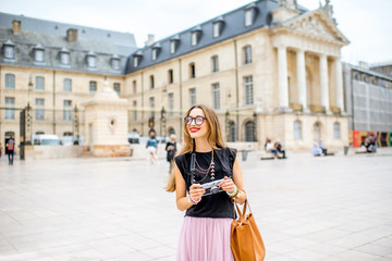 Naklejka premium Portrait of a young woman tourist with photo camera standing on the main sqaure in Dijon city, France