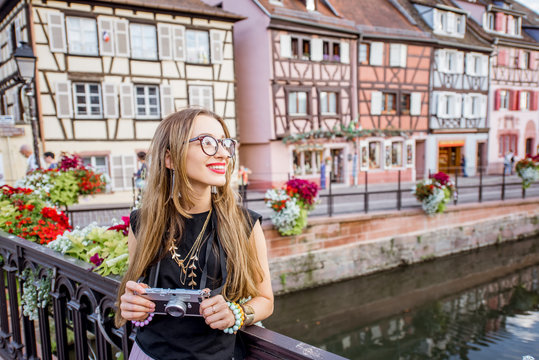 Portrait of a young woman tourist with photo camera standing on the old bridge in Colmar village in Alsace in north-eastern France