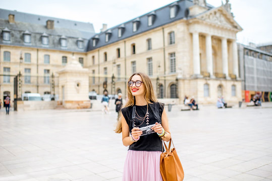 Portrait of a young woman tourist with photo camera standing on the main sqaure in Dijon city, France