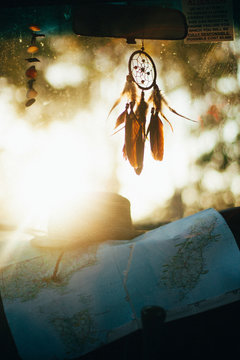 Close-up of dreamcatcher and map in car