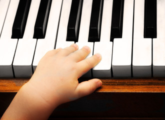 The child's hand tries to press on the piano keys