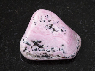 polished rhodochrosite gem on dark background