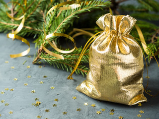 Fir branches on the grey concrete background with gold stars. New Year Christmas. Golden bag with gifts © Elenglush