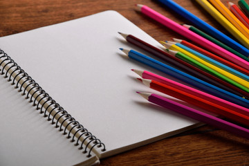 blank paper and colorful pencils on old wooden table