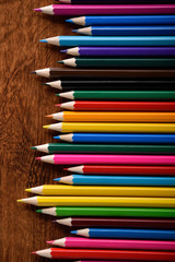 Colored crayons background. Many different colored pencils on old vintage wooden background