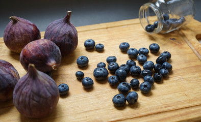 Still life of figs and blueberries on wooden board.