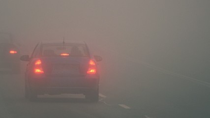 Cars in the fog. Bad winter weather and dangerous automobile traffic on the road. Light vehicles in...