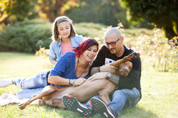 Playing with a dog in the park. Animal lovers. Mother, father, daughter and their dog