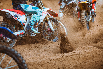 Close-up part of mountain bikes race in dirt track with flying debris during an acceleration in...