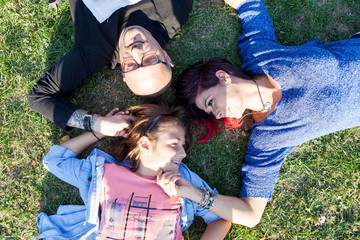 Fototapeta premium Family of three lying on the ground in the park. Mother, father, daughter