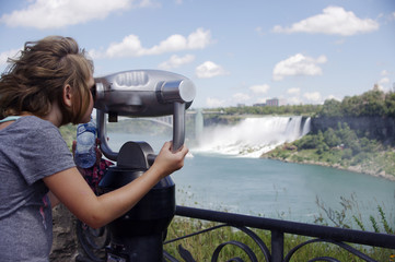 Girl looking through a viewer looking at waterfall 
