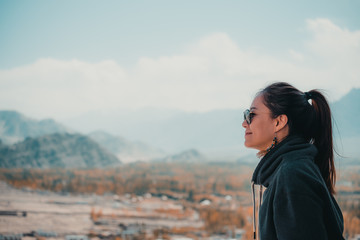 Portrait image of a beautiful Asian woman standing on the top of view point  with Leh city background