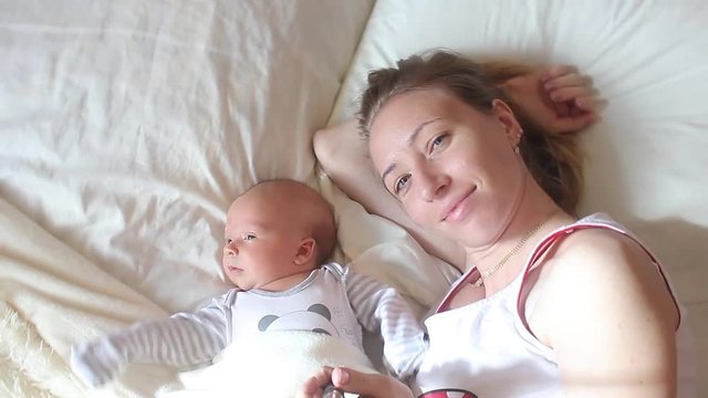 Mother and newborn baby doing selfie on bed. Resting in bed together. Maternity concept. Parenthood. Motherhood Beautiful Happy Family Stock Video Footage.