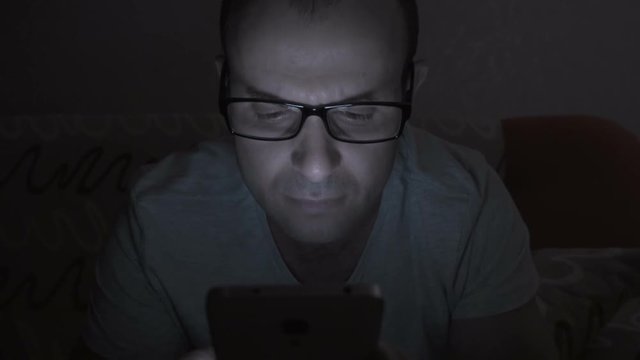 Close up of man with glasses using smartphone. Young man with tablet computer. A man at night on social networks using a smartphone.