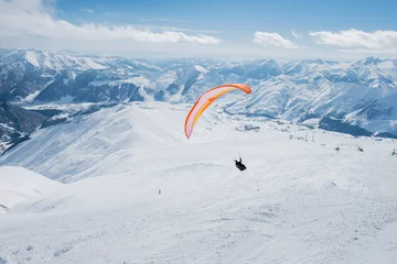 Crédence de cuisine en verre imprimé Sports aériens The sportsman on the paraglider makes a turn. flies over the snowy mountains