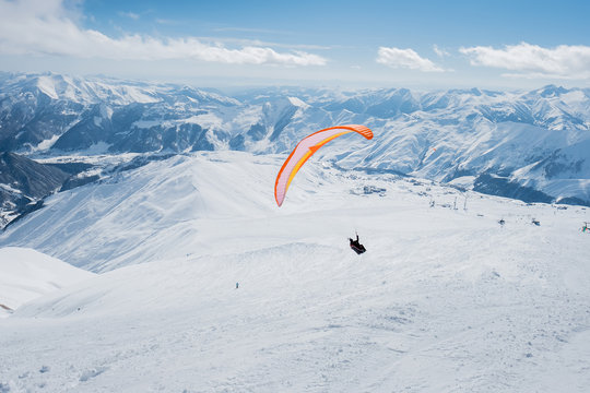 The sportsman on the paraglider makes a turn. flies over the snowy mountains