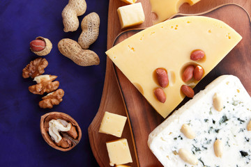 Various cheeses, apple, dried apricots, peanuts, walnuts, pears, berries, honey, jam, cheese with a mold on a wooden board in the style of pop art and retro style, Christmas cheese