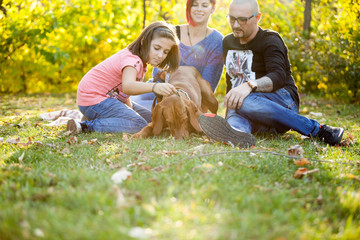 Fototapeta premium Beautiful gorgeous family of three playing in the park with their dog. Animal lovers.