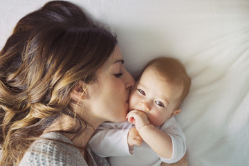 Mother and baby child on a white bed.