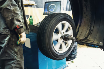 Mechanic worker makes computer wheel balancing on special equipment machine tool in auto repair service