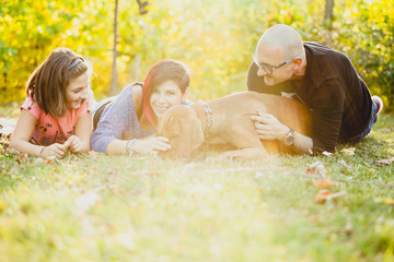 Family lying on the grass in the park with their dog. Animal lovers. Mother, father, daughter and their dog