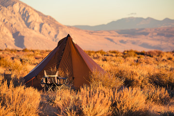 Indian style tipi tent with folding camp chair nearby pitched in the desert under the mountains of the Sierra Nevada © Jeremy Francis