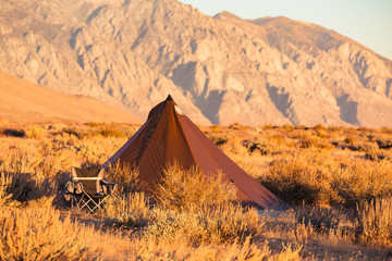Indian style tipi tent with folding camp chair nearby pitched in the desert under the mountains of the Sierra Nevada © Jeremy Francis