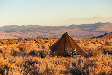 Indian style tipi tent with folding camp chair nearby pitched in the desert under the mountains of the Sierra Nevada © Jeremy Francis