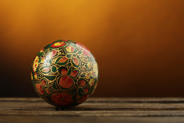 Palla di natale decorativa color fantasia sopra superficie in legno  su sfondo arancio