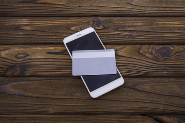 Phone and plastic card on wood table background. Conceptual presentation of payments or business activities via the Internet and mobile devices