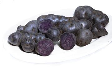 Trüffelkartoffel, Vitelotte, Blauviolette Kartoffeln auf weissem Hintergrund