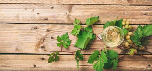 Obraz na płótnie Canvas White wine glass and fresh grapes on wooden background, copy space