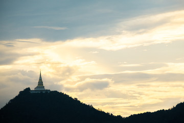 Fototapeta na wymiar Beautiful silhouette shot of golden pagoda and the temple on the high mountain at sunset.