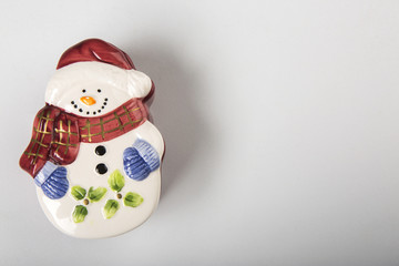 Pupazzo di neve Natalizio decorativo in ceramica con sciarpa e cappello su superfice bianca