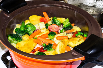 Juicy Vegetable stew, on the stove in an orange ceramic pot. Vegetarianism.
