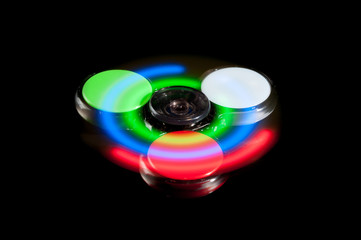 Fidget spinner with LED light in motion isolated on black background