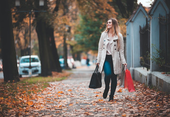 Fototapeta premium Woman with shopping bags walking in the city, casual day authentic