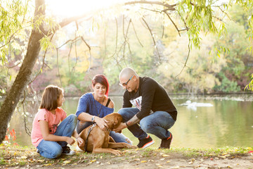 Family of father, mother and daughter on the riverside playing with their dog. Animal lovers
