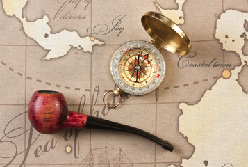 Fototapeta na wymiar tobacco pipe and compass on map