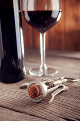Corkscrew and a glass of wine on an old wooden table