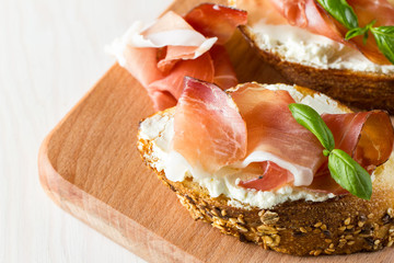 Italian tomato, prosciutto, jamon, ham and cheese bruschetta. Tapas, antipasti with chopped vegetables, herbs and oil on grilled ciabatta and baguette bread.