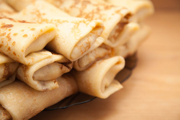 Pancakes filled with meat filling on a brown dish on an old wooden surface