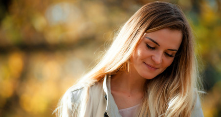 Smiling girl in coat on autumn background at sunny day