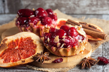 Fresh fruit tart with berries jam decorated with cranberry, mint on wooden rustic background wit a cup of tea. Desert. Morning healthy breakfast and evening dinner.