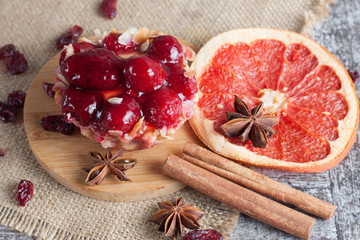 Fresh fruit tart with berries jam decorated with cranberry, mint on wooden rustic background wit a cup of tea. Desert. Morning healthy breakfast and evening dinner.