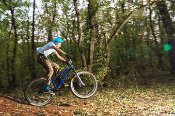 Fototapeta na wymiar a young guy in a helmet flies landed on a bicycle after jumping from a kicker