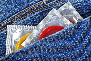 Three colored condoms in blue jeans pocket. Waiting for love and sex.