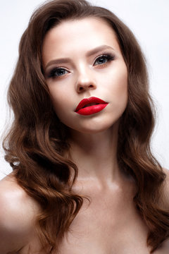 A young girl with a Hollywood wave and classic makeup. Beautiful model with red lips and arrows on eyes. Evening makeup and hairstyle. Beauty of the face.  White isolated background. Shining skin.