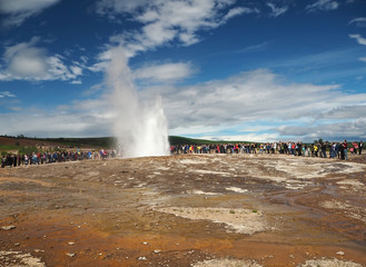 Fototapeta na wymiar ICELAND, STROKKUR, JULY 26, 2016: Strokkur geysir eruption Golden Circle, big group of colorful dressed tourist takeing pictures waiting for geyser to erupt. Strokkur is the most famous geysir