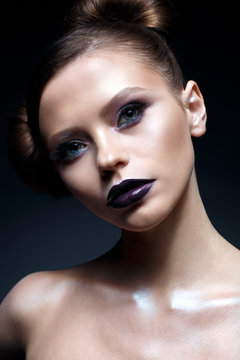 Young girl with creative makeup and hairdo. A beautiful model with bright eyes and purple lips. Shining skin. Beauty of the face. Photo taken in the studio
